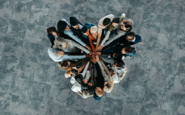 A diverse group of people standing in a circle with hands stacked together at the center