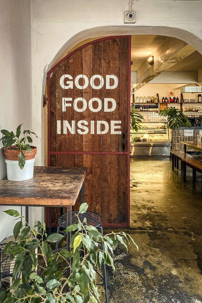 Rustic restaurant entrance with Good Food Inside painted on wooden door